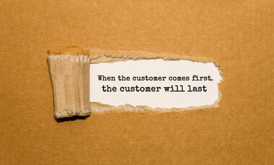 The text When the customer comes first the customer will last appearing behind torn brown paper