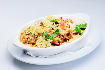 Tasting and appetizing traditional Italian lasagna dish with mushrooms served with fresh dill in a white plate isolated on black background. Autumn menu in an Italian restaurant