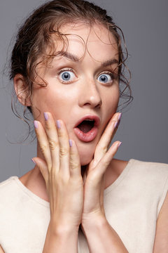Amazed young woman with hands near face and mouth open
