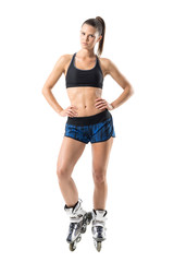 Confident serious inline roller skates young female in akimbo pose looking at camera. Full body length portrait isolated on white studio background.