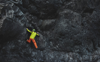 male rock climber. rock climber climbs on a black rocky wall on the ocean bank in Iceland,...