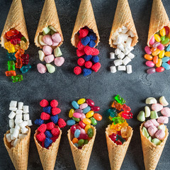 Assorted candy in waffle cones. Summer concept, food frame. Flat lay, top view