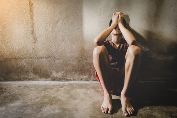 Abused boy crying in the corner of his home because of domestic violence