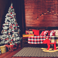 Beautiful Christmas interior design. Room decorated with wooden sofa with warm blanket, lights, teddy bear and wooden horse, toned image. Concept of Merry Christmas, winter and New year