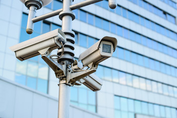 Public city video surveillance cameras on the lamppost over sky, close-up