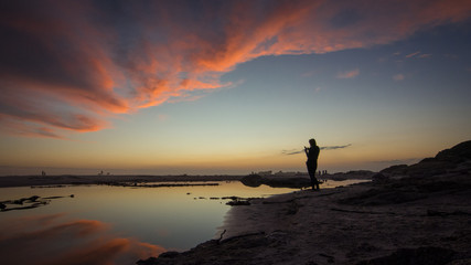 Next to the lagoon on Noordhoek Beach, a photographer watches the sunset