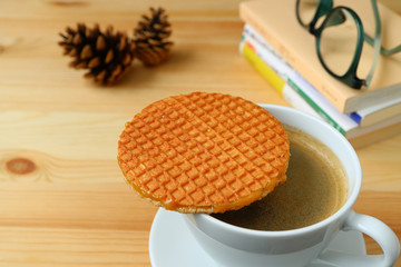 Spending Some Quiet Time with Stroopwafel and a Cup of Hot Coffee served on wooden table, Blurred Background 