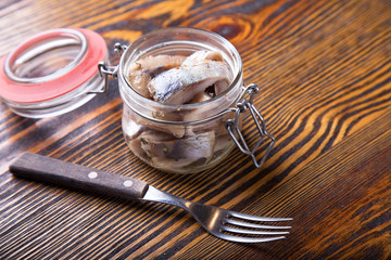 Herring in a jar on a wooden table