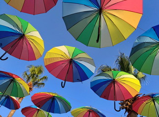 Multicolored umbrellas against the sky in the backlight