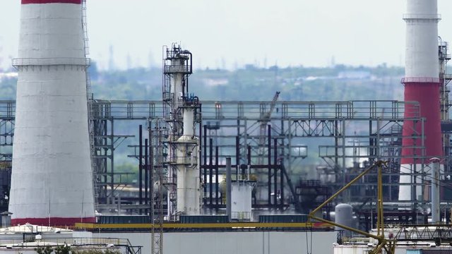 Long shot of oil refinery units in sunny weather with clouds in background. Gas industry background.