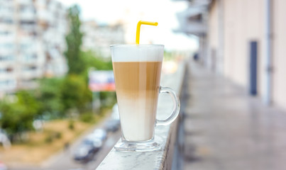 strong high clean glass cup with latte against blue sky with white clouds
