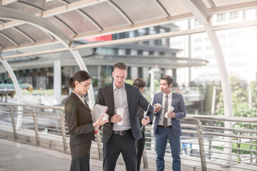 Fototapeta premium Business colleagues walking outside office & talking to each other. Businessman talk and hold coffee cup