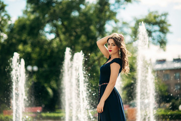A girl is walking around the city, near a large fountain. Sunny day. Summer