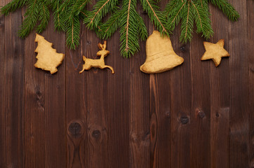 Christmas composition of fir branches and homemade cookies on a wooden background