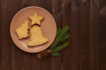 Fototapeta premium homemade cookies in the form of spruce, stars, bells on a pink plate on a wooden background.