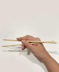 Woman hand holding chopsticks on white background