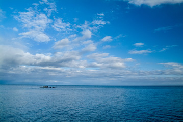 Naklejka na ściany i meble Calm morning sea landscape with cloudy sky and rocks. wide angle. Horizontal frame