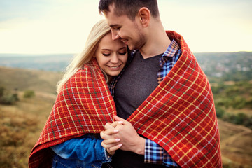 Happy couple under a plaid outdoors. Valentine's Day.