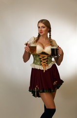 Blond young presses to her breast two mugs of light and dark beer in a national costume Czech with a hair pigtail stands on a white background smiling looks to the camera