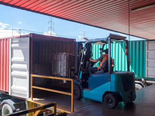 Forklift unstuffing tank of solvent from container to storange in warehouse. © Amarinj