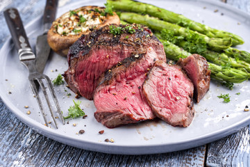 Barbecue wagyu point steak with green asparagus and mushroom cap as close-up on a plate