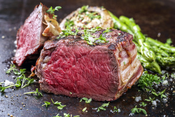 Barbecue wagyu point steak with green asparagus and mushroom cap as close-up on a rusty metal sheet