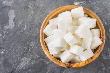 wooden bowl with white sugar cubes on dark background