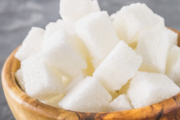 wooden bowl with white sugar cubes on dark background