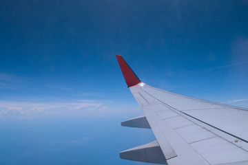 Airplane wing on bright clear blue sky with some cloud can see horizontal line from window shade