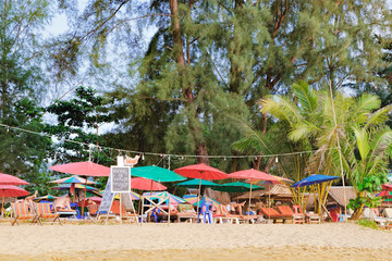 Tourists have a rest, walk and watch the colorful sunset at Nang Thong Beach, Andaman Sea, Khao Lak, Thailand. Relaxing on paradise beach with palms trees
