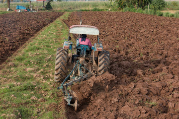 Farmer using machine in rice field,Farmer in tractor preparing farmland.