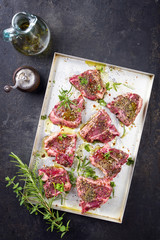 Raw t-bone lamb steak with seasonings as top view on a tray