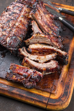 Barbecue pork spare ribs as top view on a burnt cutting board