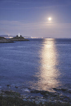 Full moon and lighthouse at Mumbles Head. Wales, UK.