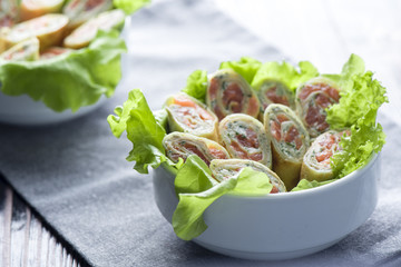 Pancake rolls with salmon and greens in a white bowl