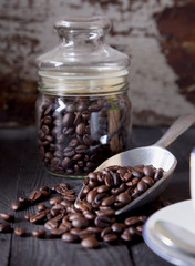 Roast coffee beans in metal scoop on black wood table