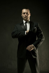 The attractive man in black suit on dark background