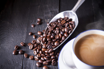 Roast coffee in metal scoop on black wood table