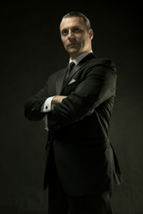 The attractive man in black suit on dark background