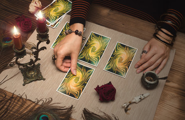 Fortune teller reading tarot cards on wooden table.