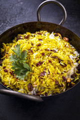 Indian vegetarian biryani with nuts and raisins as close-up in a korai