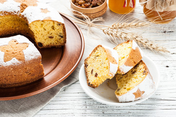 homemade traditional fruit cake slices decorated with nuts and wheat ears at white wooden table