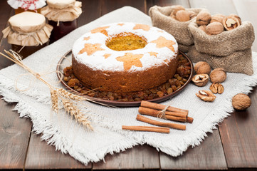 Obraz na płótnie Canvas homemade traditional fruit cake on clay plate decorated with wheat ears, nuts and honey jars at wooden table