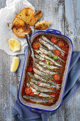 Sardinas en salsa with garlic bead as top view in a skillet