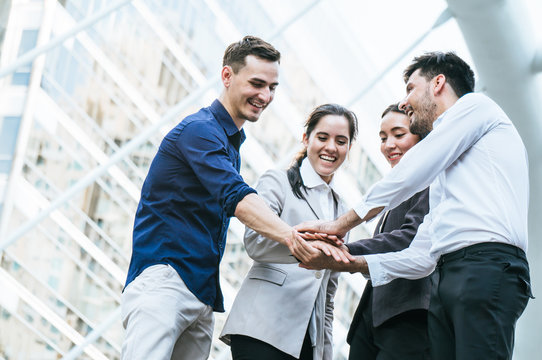 Businessman with colleagues stacking hand to cooperate on building background outdoor in city