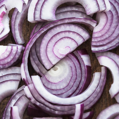 Food preparation, cooking concept: pattern of sliced fresh red onions on rustic wooden background