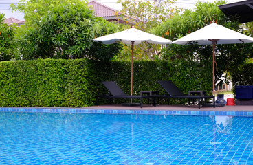 two chairs with white umbrella beside a pool