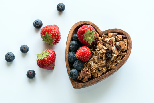 Healthy breakfast: homemade gramola with fresh blueberry and strawberry on white background