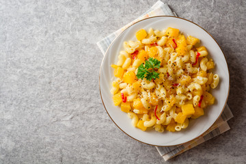 Pasta with pumpkin, chili and cheese in plate on stone background