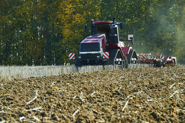Seasonal work in a agricultural landscape. Tractor plowing the field.